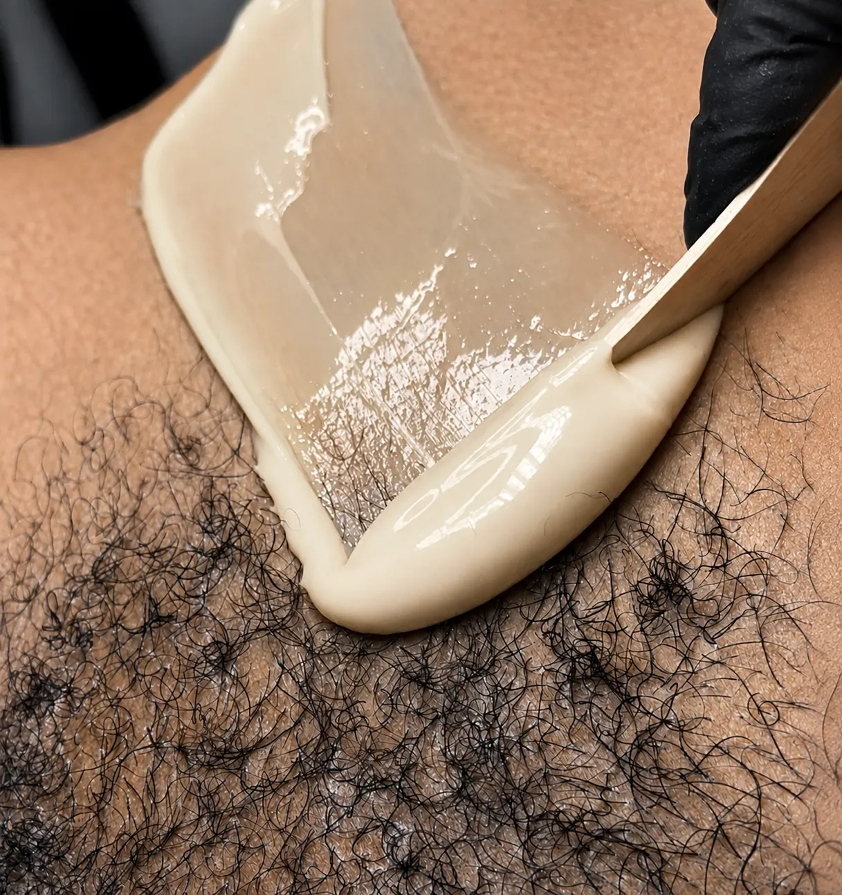 Warm wax being applied with a spatula during a professional waxing treatment
